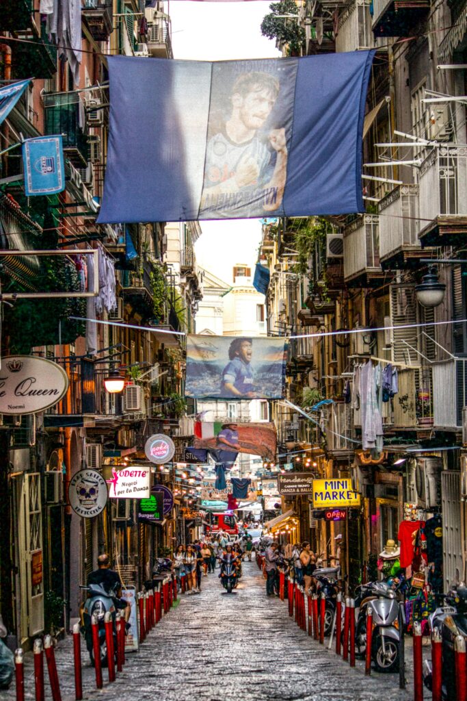 Explore the bustling streets of Naples adorned with colorful banners and lively urban scenes.