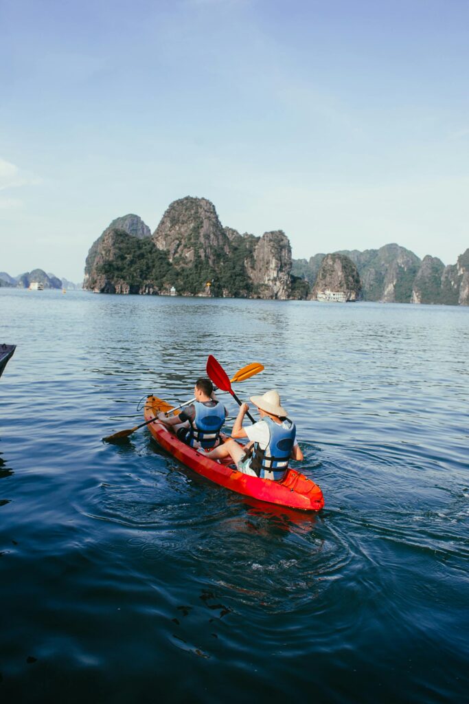 Two people kayaking in Halong Bay, Vietnam, surrounded by stunning rock formations.