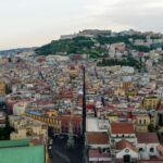 Drone shot of Naples showcasing vibrant cityscape and iconic Castel Sant'Elmo on a cloudy day.