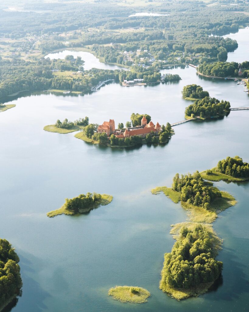 Aerial view of Trakai Castle surrounded by picturesque lakes and green islands in Lithuania.
